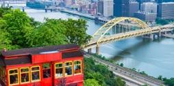 Photo of 匹兹堡's red incline car framing the city's skyline in the distance. 